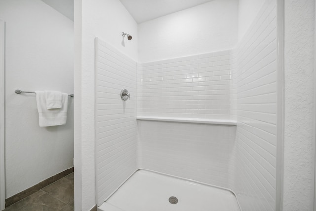 bathroom featuring tiled shower, baseboards, and tile patterned floors