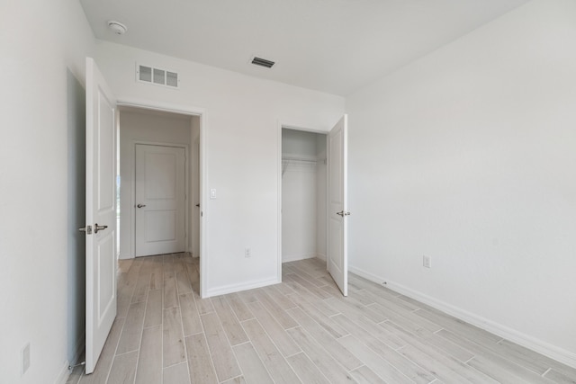 unfurnished bedroom featuring wood tiled floor, a closet, visible vents, and baseboards