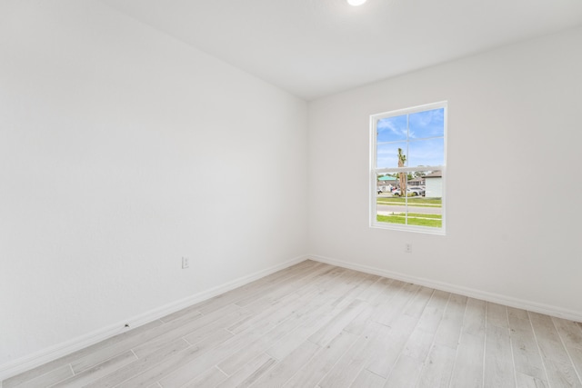 spare room featuring light wood-style floors and baseboards