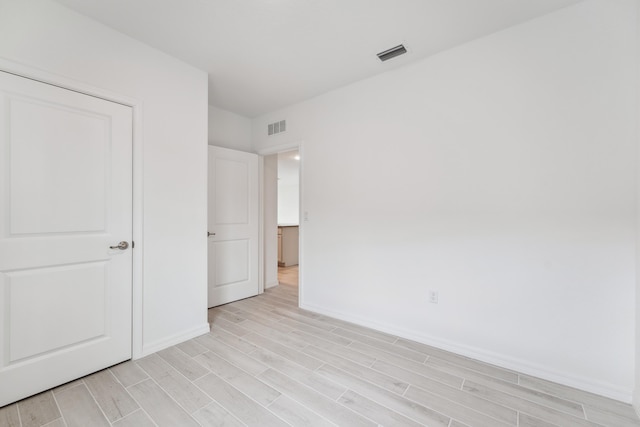 unfurnished bedroom with baseboards, visible vents, and wood finish floors