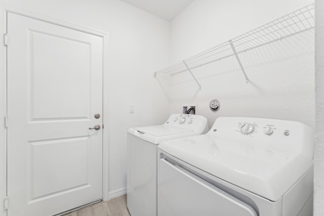 laundry room with washer and dryer, laundry area, baseboards, and light wood finished floors