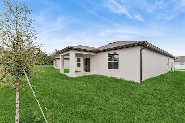 back of house featuring stucco siding and a yard