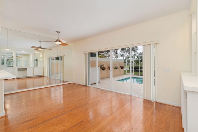 unfurnished living room with ceiling fan, baseboards, and wood finished floors