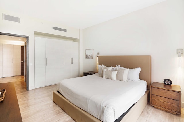 bedroom featuring a closet, visible vents, and light wood-style flooring