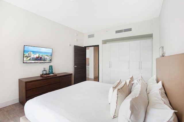 bedroom with light wood-style flooring, visible vents, and baseboards