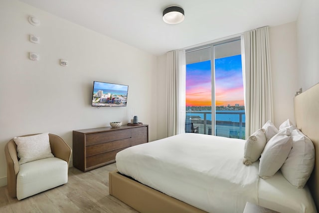 bedroom with access to outside, floor to ceiling windows, and light wood finished floors