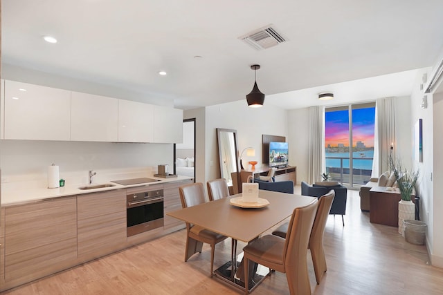 kitchen with stainless steel oven, white cabinets, light countertops, modern cabinets, and pendant lighting