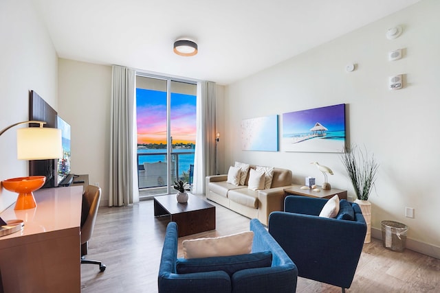 living area with a wall of windows, baseboards, and wood finished floors