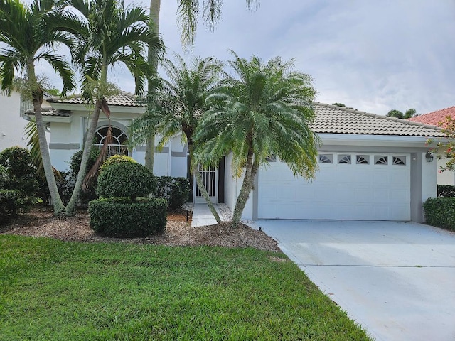 mediterranean / spanish home with a garage, a tile roof, concrete driveway, and stucco siding