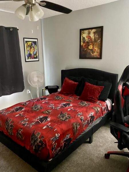 bedroom featuring carpet floors, a textured ceiling, and a ceiling fan