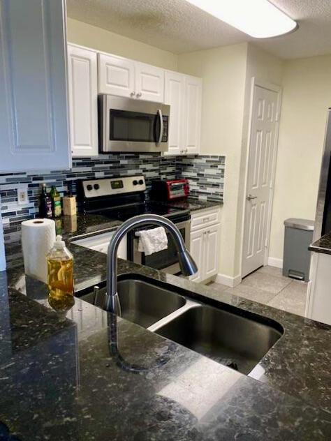 kitchen featuring a textured ceiling, stainless steel appliances, a sink, and white cabinets