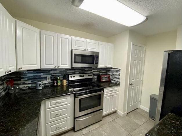 kitchen featuring stainless steel appliances, white cabinetry, and decorative backsplash