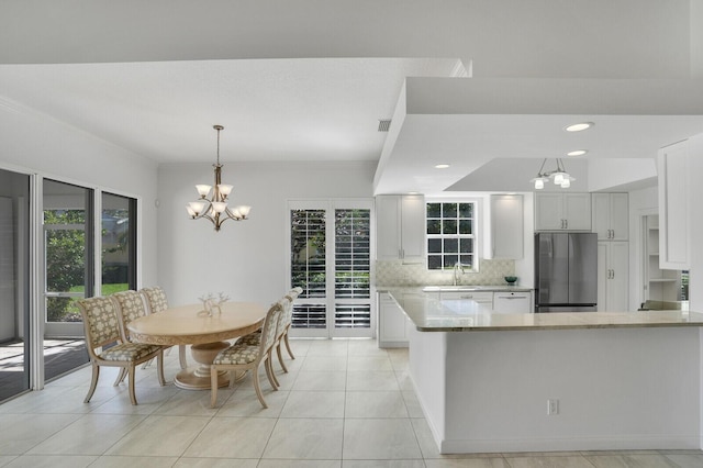 kitchen with decorative light fixtures, a notable chandelier, white cabinets, a sink, and stainless steel fridge