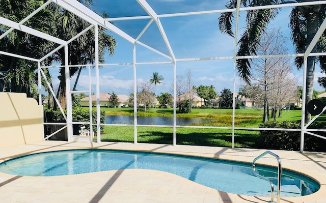 pool with a patio area, glass enclosure, a water view, and a lawn