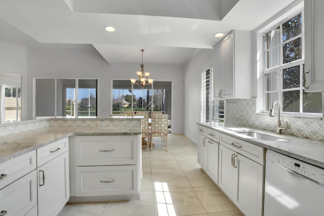 kitchen with tasteful backsplash, white cabinets, white dishwasher, a sink, and light stone countertops