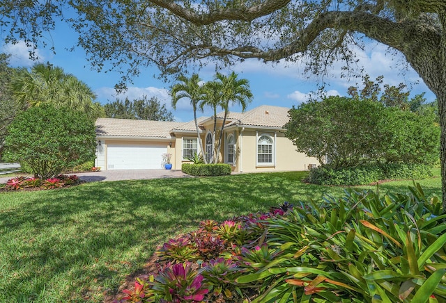 ranch-style home featuring a garage, stucco siding, a front yard, a tiled roof, and driveway