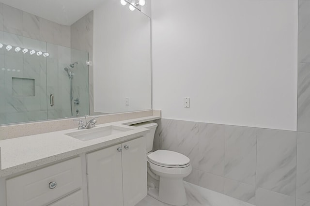 bathroom featuring a marble finish shower, wainscoting, toilet, vanity, and tile walls