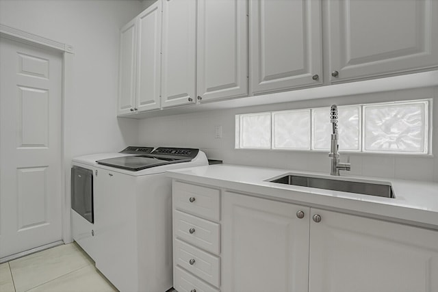 washroom featuring a sink, light tile patterned floors, washing machine and clothes dryer, and cabinet space