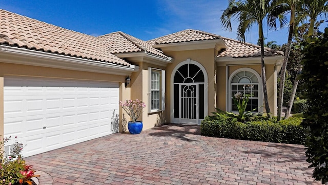 view of front of home with a garage, a tiled roof, decorative driveway, and stucco siding