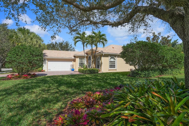 mediterranean / spanish-style house with an attached garage, a tiled roof, a front yard, and stucco siding