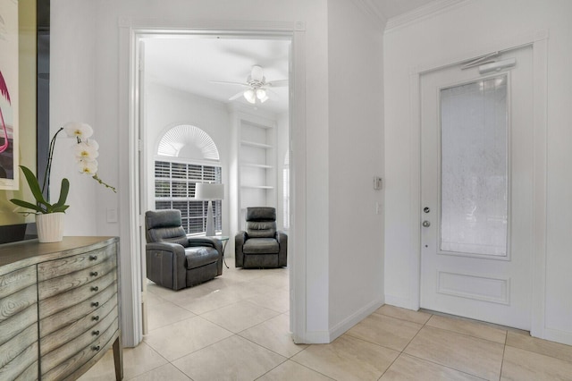entryway with baseboards, a ceiling fan, light tile patterned floors, and ornamental molding