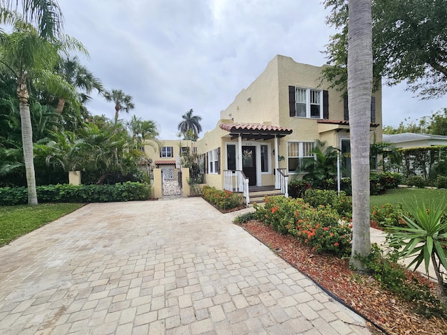 mediterranean / spanish home with a tile roof, a gate, and stucco siding