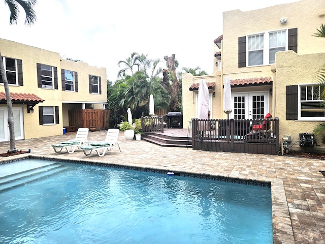 outdoor pool featuring french doors, a patio, grilling area, and fence