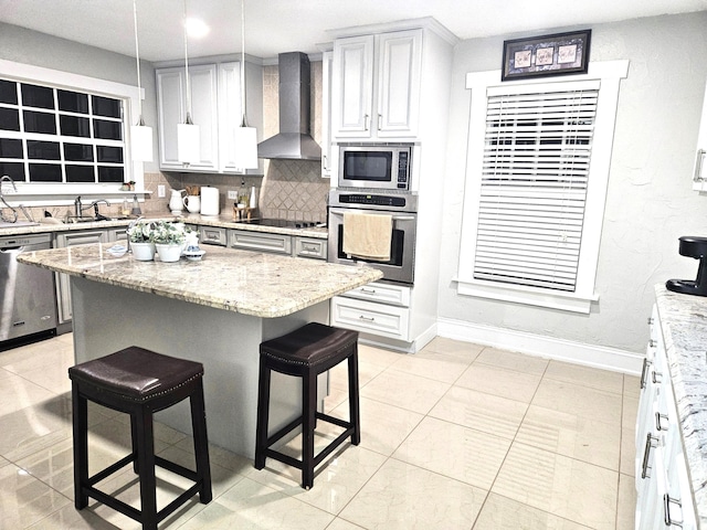 206 Edgewood Dr, West Palm Beach, FL 33405 - kitchen with a kitchen bar, light stone counters, decorative backsplash, stainless steel appliances, and wall chimney exhaust hood