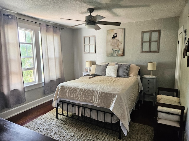 bedroom with a textured ceiling, a textured wall, ceiling fan, wood finished floors, and baseboards