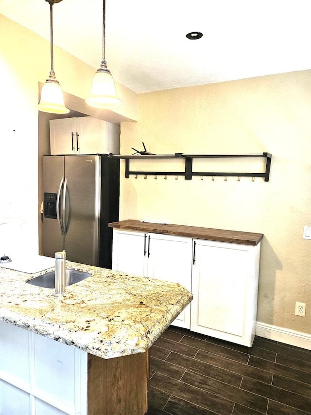 206 Edgewood Dr, West Palm Beach, FL 33405 - kitchen featuring wood finish floors, pendant lighting, white cabinets, stainless steel fridge with ice dispenser, and baseboards