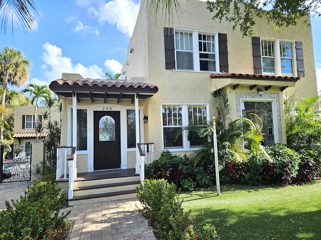 view of front of home with a front yard, a tiled roof, and stucco siding