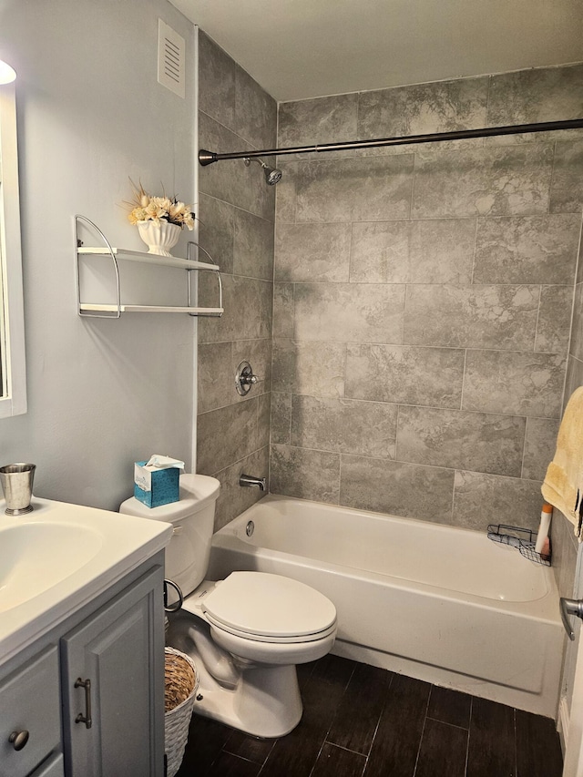 bathroom with visible vents, toilet, vanity, shower / bathtub combination, and wood finish floors