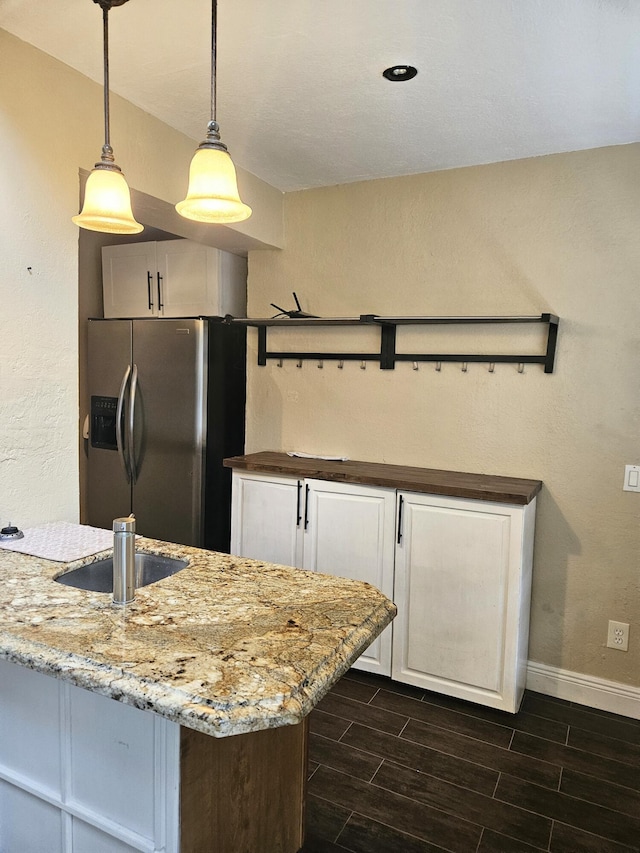 kitchen featuring wood tiled floor, white cabinets, hanging light fixtures, and stainless steel fridge with ice dispenser