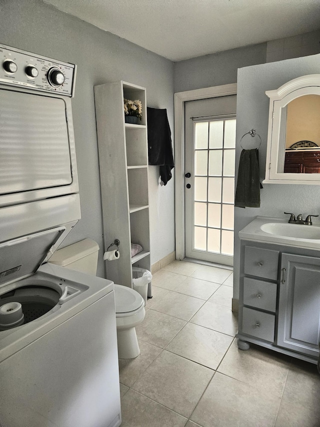 bathroom featuring toilet, tile patterned floors, stacked washer / drying machine, and vanity