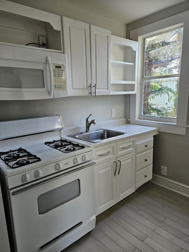 kitchen featuring open shelves, light countertops, white cabinets, a sink, and white appliances