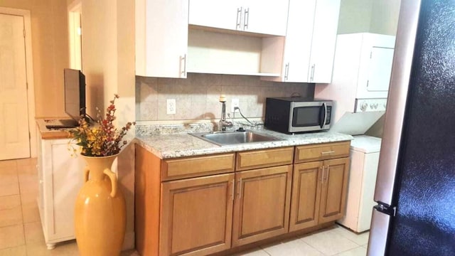 206 Edgewood Dr, West Palm Beach, FL 33405 - kitchen featuring a sink, decorative backsplash, stacked washer / drying machine, appliances with stainless steel finishes, and brown cabinets