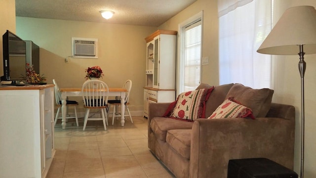 living area featuring light tile patterned floors, baseboards, a textured ceiling, and an AC wall unit