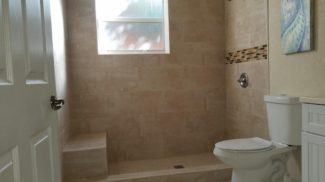 bathroom featuring vanity, a tile shower, and toilet