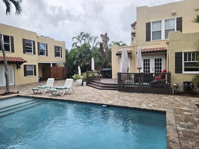 pool featuring a patio, grilling area, fence, a deck, and french doors