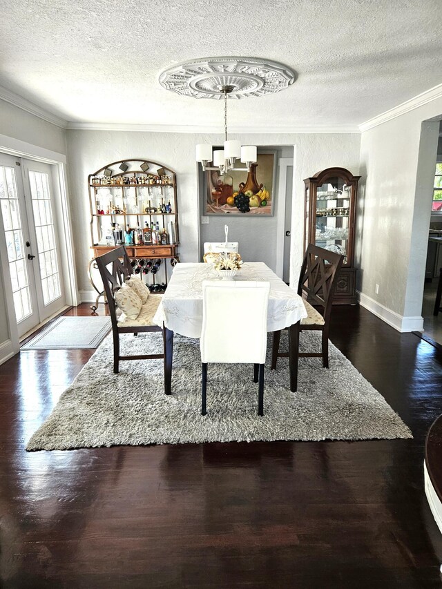 206 Edgewood Dr, West Palm Beach, FL 33405 - dining area featuring crown molding, baseboards, wood finished floors, a notable chandelier, and a textured ceiling