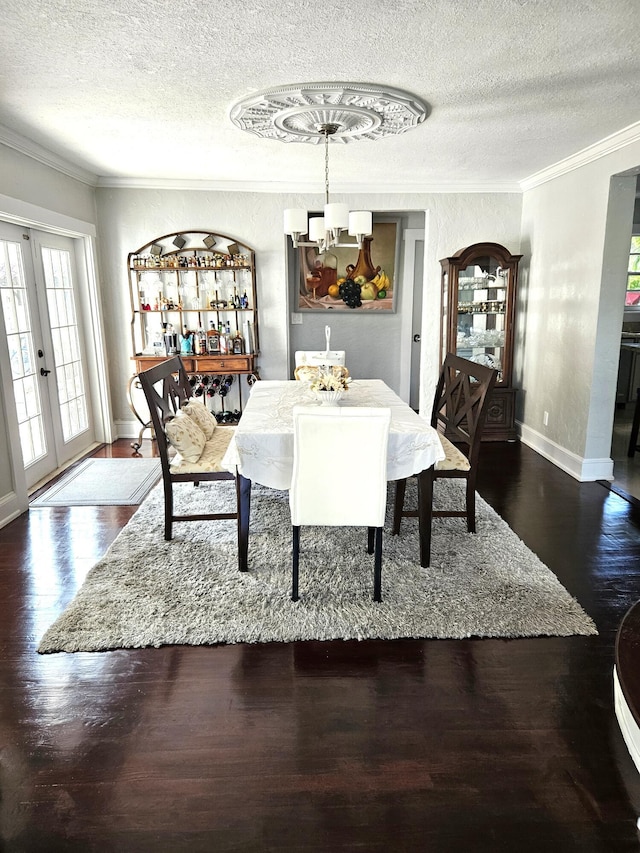 dining room with french doors, crown molding, a textured ceiling, wood finished floors, and baseboards