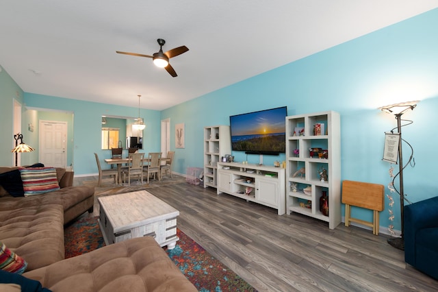 living area with dark wood-style floors, a ceiling fan, and baseboards