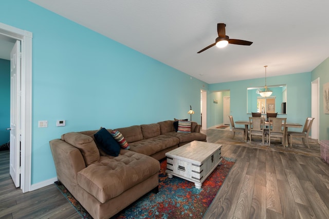 living room featuring dark wood-type flooring, ceiling fan, and baseboards