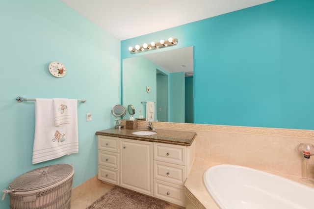 full bath featuring tiled tub, vanity, and tile patterned floors