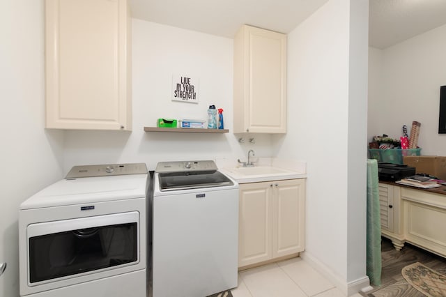 clothes washing area featuring washing machine and dryer, cabinet space, a sink, and baseboards