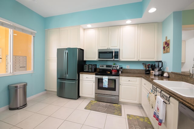 kitchen with stainless steel appliances, dark countertops, recessed lighting, white cabinetry, and a sink