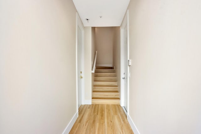 corridor featuring stairs, baseboards, and wood finished floors