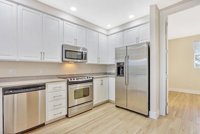 kitchen featuring light wood finished floors, stainless steel appliances, light countertops, white cabinetry, and recessed lighting