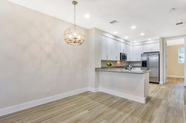 kitchen featuring stainless steel appliances, a peninsula, visible vents, white cabinets, and hanging light fixtures