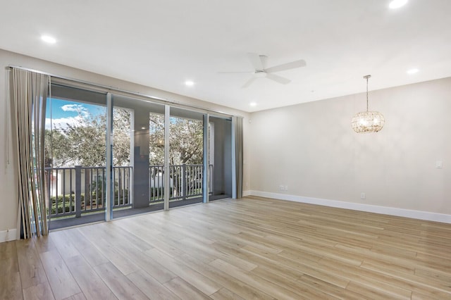 spare room with recessed lighting, light wood-style flooring, baseboards, and ceiling fan with notable chandelier